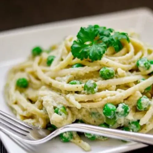 This mouthwatering recipe combines perfectly cooked linguine with a rich and creamy pesto sauce, all adorned with a generous sprinkle of gooey cheese and a burst of vibrant peas.