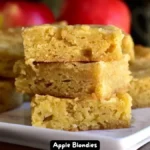 A close-up of moist and flavorful apple blondies with a dusting of powdered sugar.