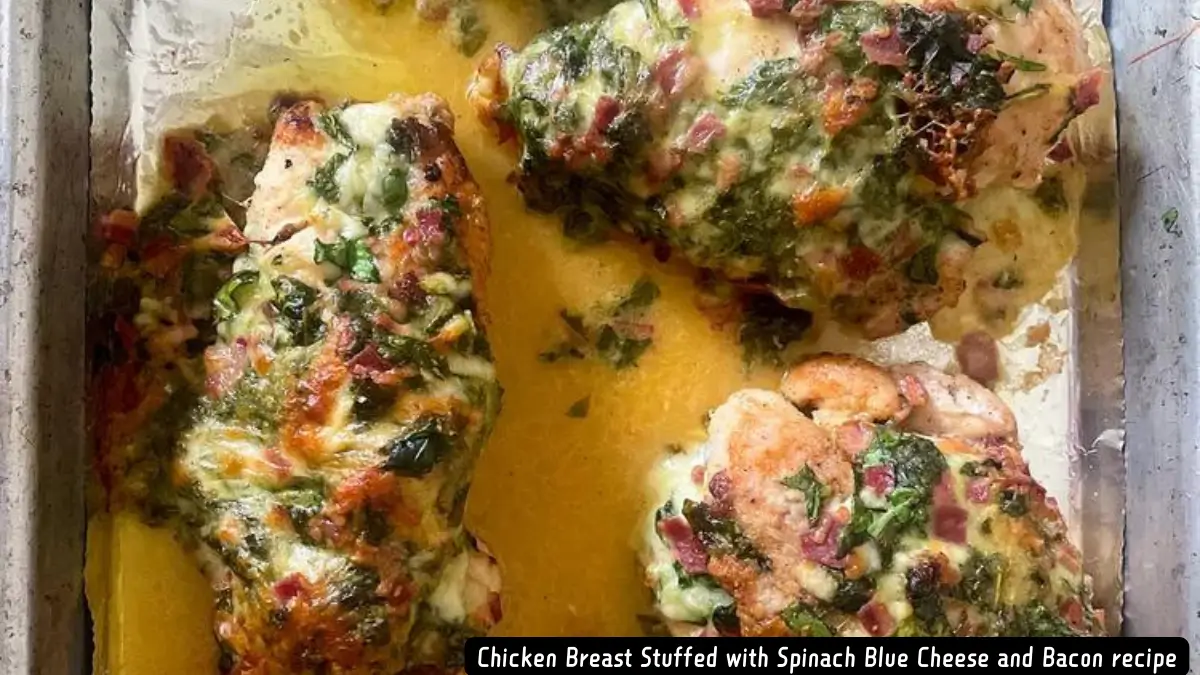 A close-up view of baked chicken breasts stuffed with spinach, blue cheese, and bacon, glistening with melted cheese and juices.