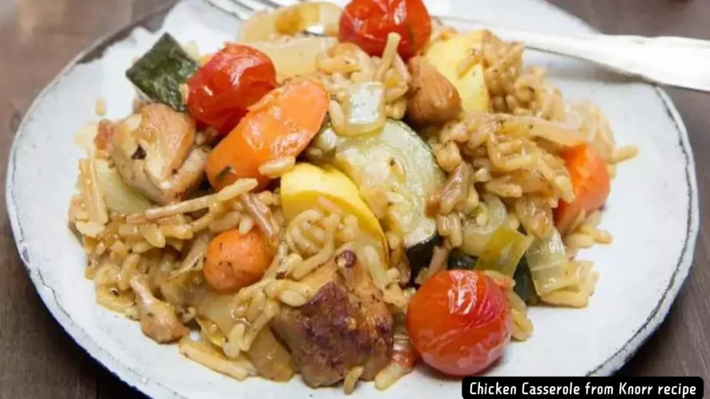 A plate of delicious chicken casserole featuring colorful vegetables like cherry tomatoes, carrots, zucchini, and yellow squash mixed with seasoned rice.