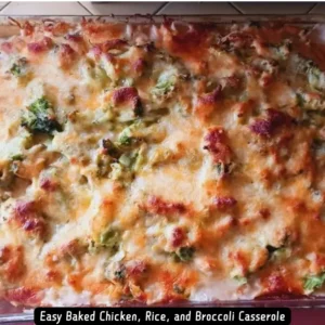 A delicious and easy baked chicken, rice, and broccoli casserole in a baking dish, topped with melted cheddar cheese.