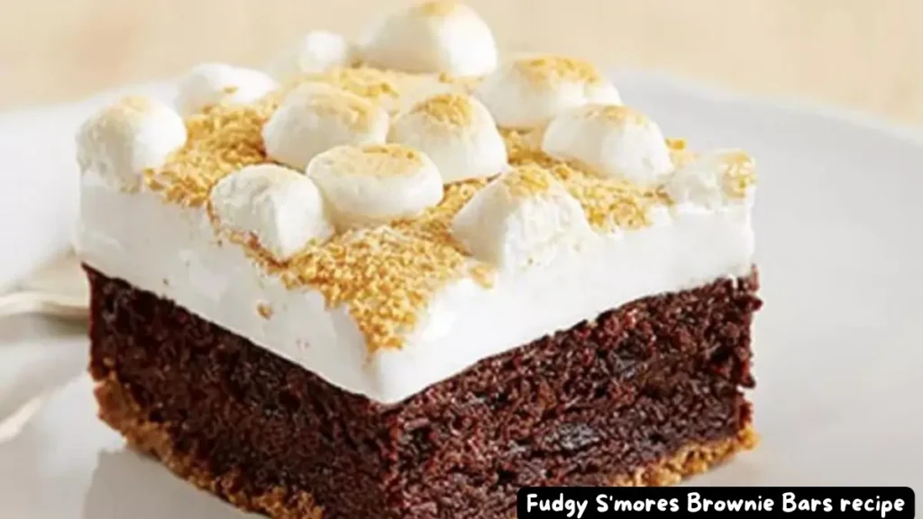 A close-up of a single piece of Fudgy S'mores Brownie Bar showing layers of chocolate brownie, marshmallow topping, and graham cracker crumbs.