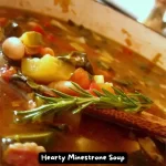 A bowl of hearty minestrone soup filled with vegetables, beans, and pasta.