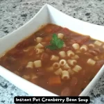 A bowl of hearty Instant Pot Cranberry Bean Soup garnished with fresh parsley and Pecorino Romano cheese.