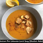 Bowl of Instant Pot Lebanese Lentil Soup garnished with pita chips and lemon wedges