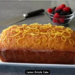 A freshly baked lemon drizzle cake with a golden brown crust and a glossy lemon glaze.