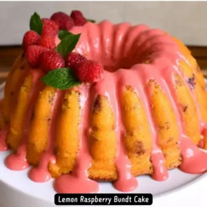 A beautifully glazed Lemon Raspberry Bundt Cake garnished with fresh raspberries, mint leaves, and slivered almonds.