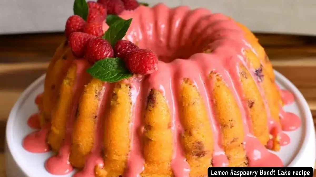 A beautifully baked Lemon Raspberry Bundt Cake drizzled with vibrant pink raspberry glaze and garnished with fresh raspberries and mint leaves.