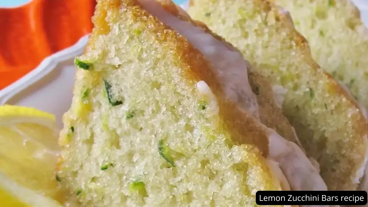 Close-up view of a slice of lemon zucchini bar showcasing its moist and fluffy texture with visible bits of zucchini, served with lemon slices.