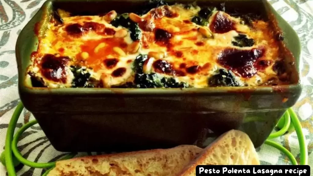 A delicious Pesto Polenta Lasagna with melted cheese and toasted pine nuts in a rectangular baking dish.