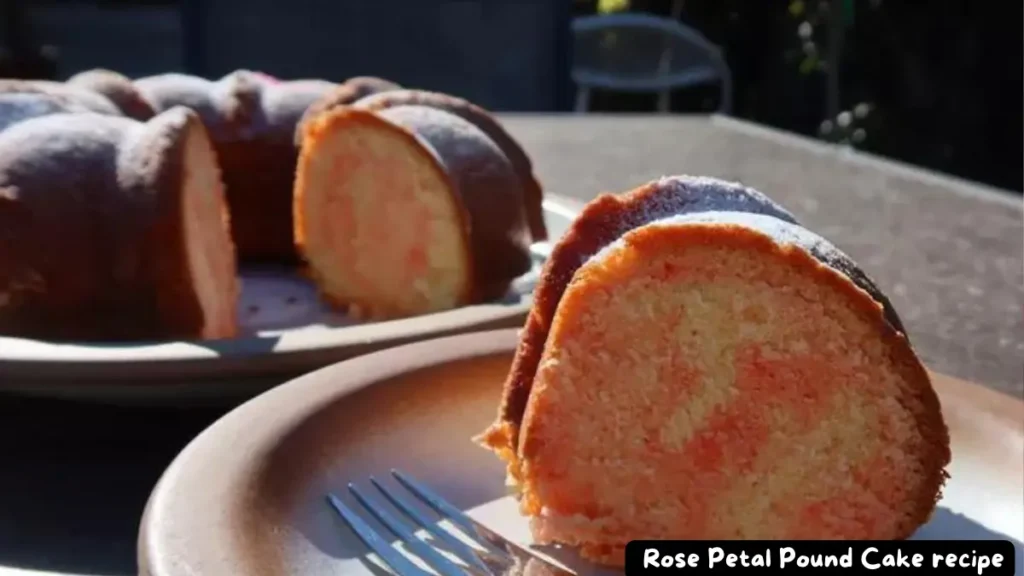 A slice of Rose Petal Pound Cake on a plate with a fork, showcasing its marbled pink and yellow interior.