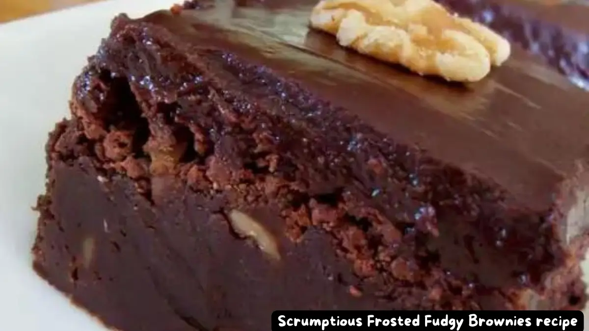 Close-up of a rich and chocolaty frosted fudgy brownie with a walnut garnish.