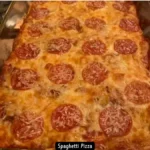 A delicious slice of baked spaghetti pizza with melted cheese and pepperoni.