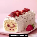 A freshly made strawberry cream roll cake, decorated with fresh strawberries and a dusting of powdered sugar