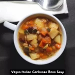 A bowl of Vegan Italian Garbanzo Bean Soup garnished with fresh herbs.