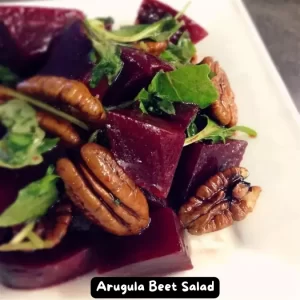 A vibrant bowl of arugula beet salad with walnuts, ready to be served