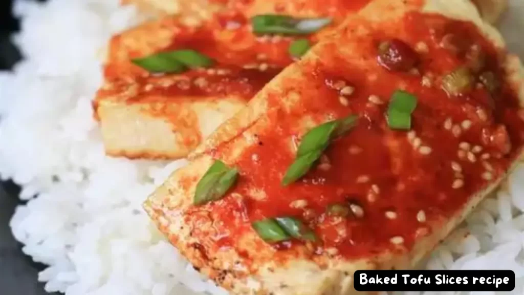 Close-up of baked tofu slices topped with spicy soy sauce, garnished with green onions, served over a bed of white rice.