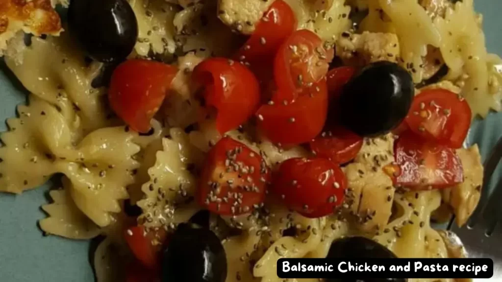 A close-up of balsamic chicken and bowtie pasta garnished with cherry tomatoes, black olives, and herbs, served on a blue plate.