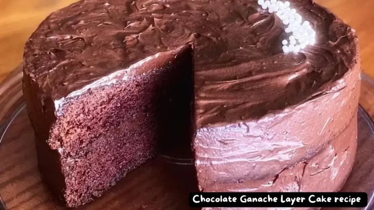 A rich and gooey chocolate ganache layer cake with a slice cut out, showcasing its moist texture and glossy ganache frosting.