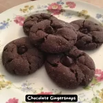 A plate of freshly baked Chocolate Gingersnaps with a crackled surface and visible chocolate chips.