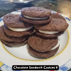 Moist and chewy chocolate sandwich cookies with a creamy filling on a white plate.