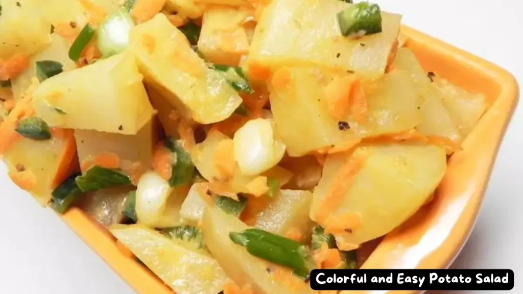A bowl of colorful potato salad with cubed potatoes, grated carrots, sliced green onions, and diced Hatch chile pepper.