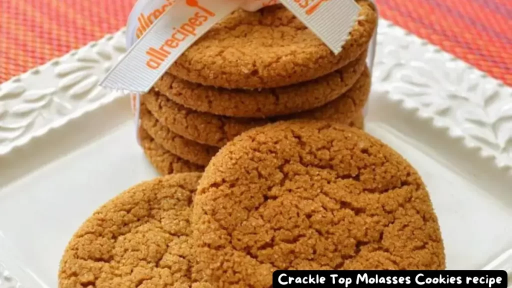 A stack of golden-brown Crackle Top Molasses Cookies tied with a ribbon, presented on a white plate.