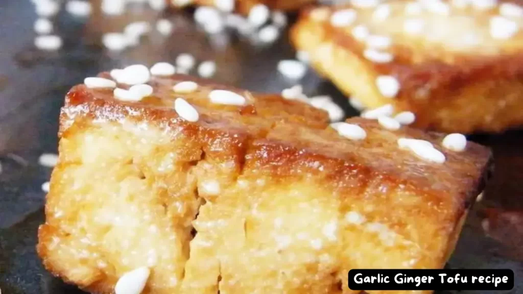 Close-up of a slice of garlic ginger tofu garnished with sesame seeds.