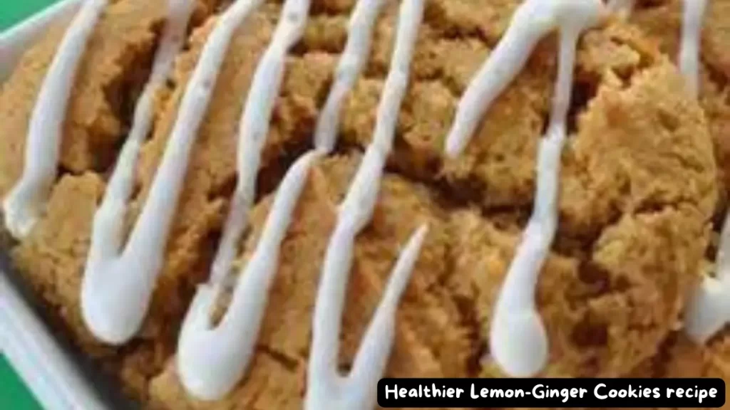 A close-up view of healthier lemon-ginger cookies with a drizzle of white icing on top, presented in a baking tray.