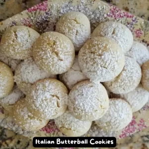 A plate of Italian Butterball Cookies dusted with confectioners' sugar, ready to be enjoyed.