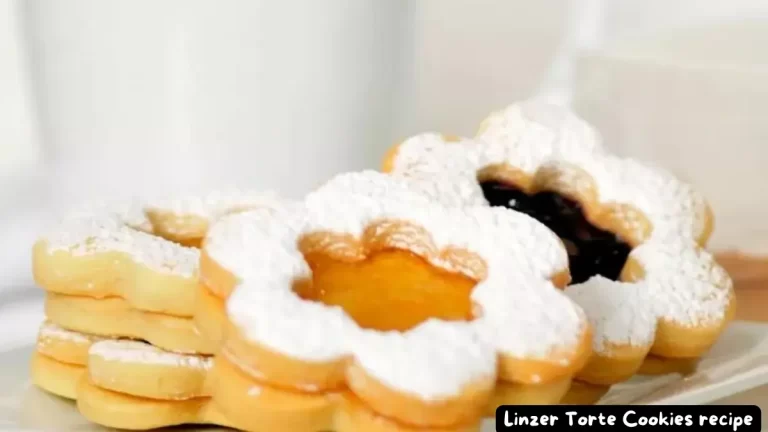 A stack of Linzer Torte Cookies filled with apricot and raspberry jam, dusted with powdered sugar.