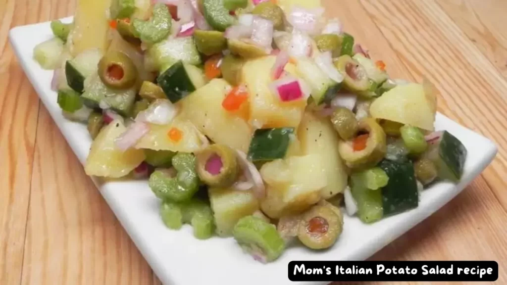 A delicious serving of Mom's Italian Potato Salad featuring potatoes, green olives, celery, and red onions on a white plate.