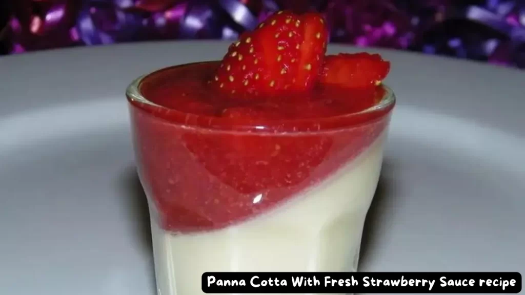 A glass of panna cotta topped with fresh strawberry sauce and strawberry slices.