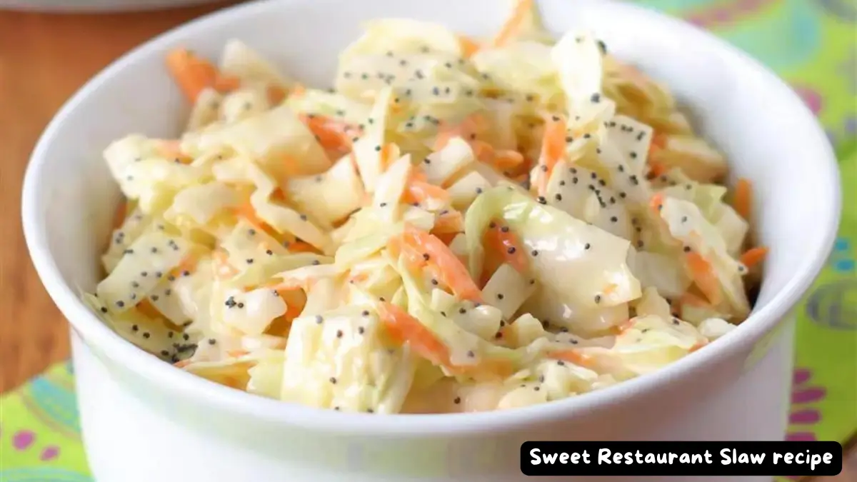 A white bowl filled with sweet restaurant slaw garnished with poppy seeds.