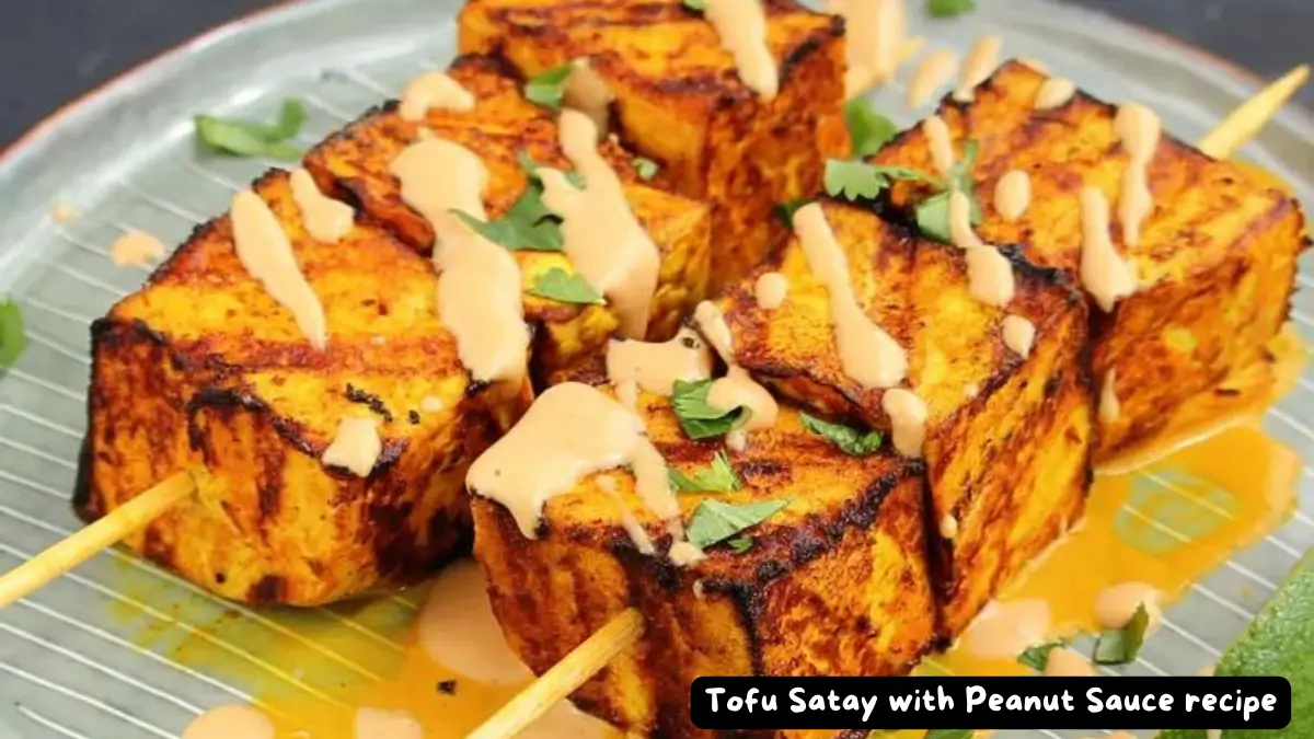 Close-up of grilled tofu satay skewers drizzled with creamy peanut sauce, garnished with fresh herbs