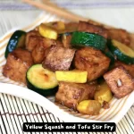 A vibrant stir fry with yellow squash, zucchini, and tofu in a skillet.