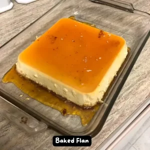 A beautifully caramelized baked flan served on a white plate with a slice topped with golden sugar syrup