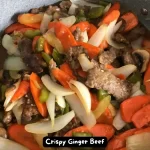 A plate of crispy ginger beef with vibrant fresh vegetables.