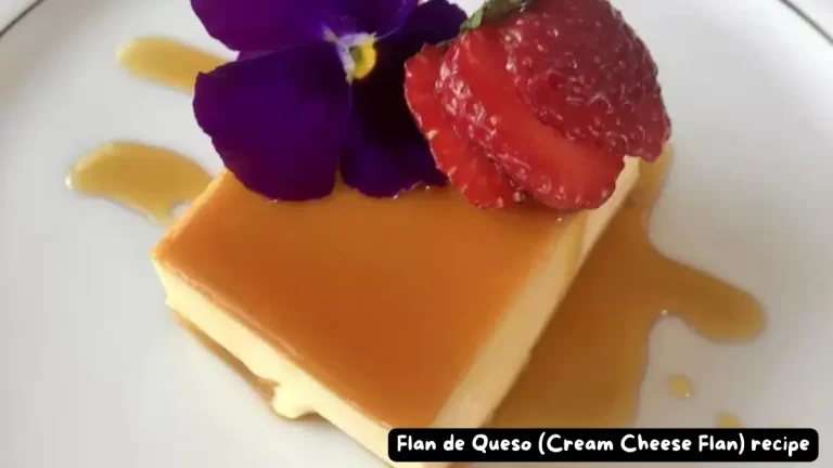 A slice of creamy Flan de Queso topped with golden caramel, garnished with a purple flower and fresh strawberry.