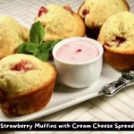 A batch of freshly baked strawberry muffins served with a strawberry cream cheese spread