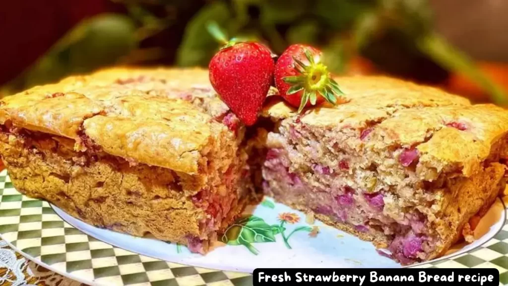 A loaf of freshly baked strawberry banana bread with a slice cut out, revealing the juicy strawberries inside, adorned with fresh strawberries on top.