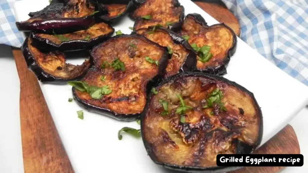 A plate of beautifully grilled eggplant slices garnished with fresh herbs.