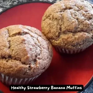 A dozen golden-brown healthy strawberry banana muffins on a cooling rack.