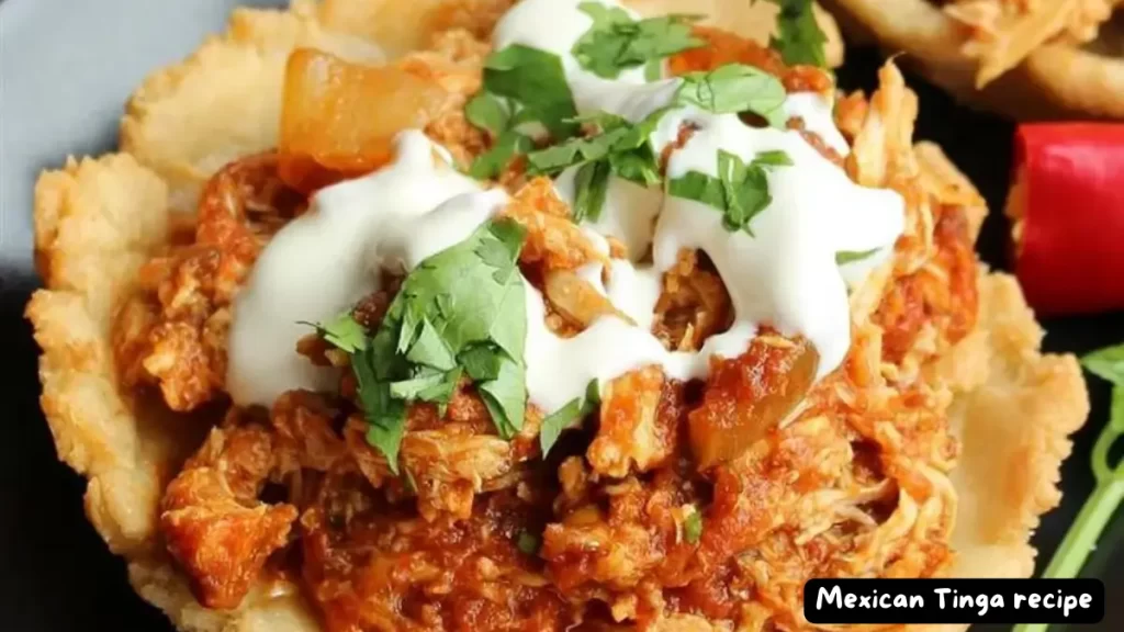 Close-up of Mexican Tinga served on a crispy tostada shell, topped with fresh cilantro and sour cream.