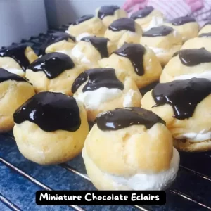 A plate of homemade miniature chocolate eclairs filled with chocolate pudding and topped with a chocolate glaze.