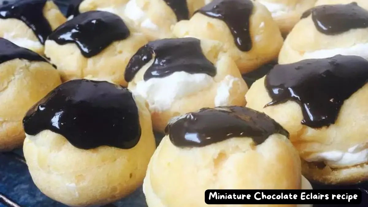 A close-up of several miniature chocolate eclairs filled with cream and topped with a glossy chocolate glaze.