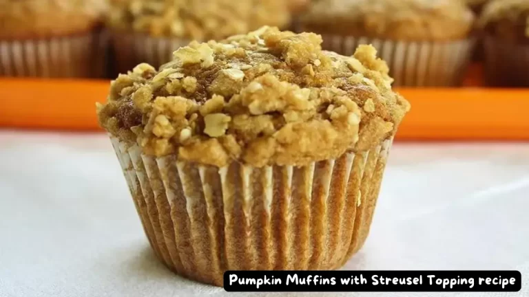 A close-up of a pumpkin muffin topped with a crumbly streusel, surrounded by other muffins.