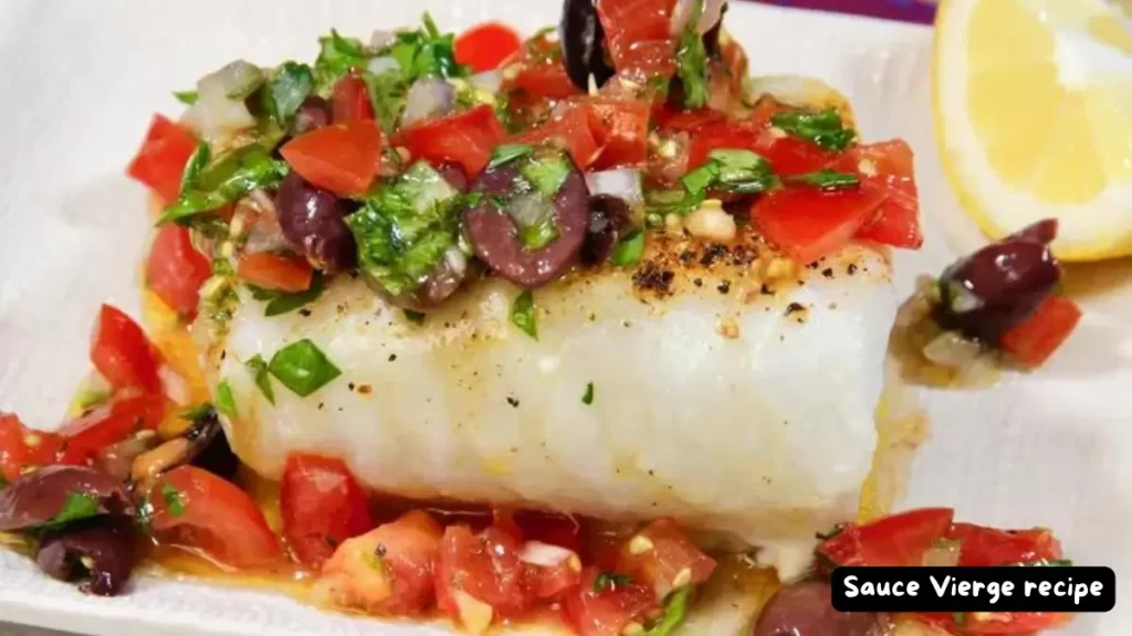 A serving of white fish topped with fresh Sauce Vierge, surrounded by diced tomatoes and herbs, with a lemon wedge on the side.