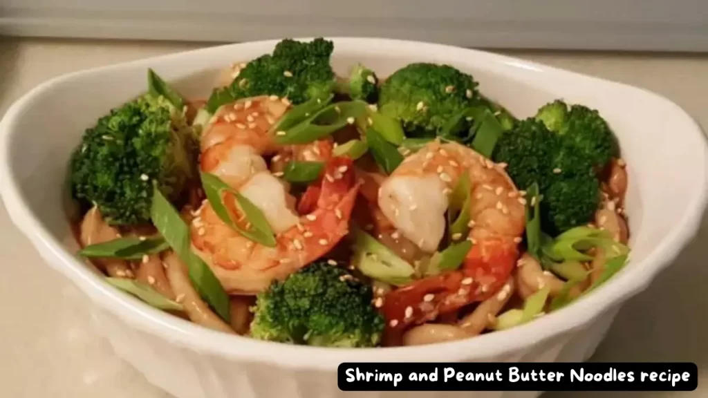 A delicious bowl of Shrimp and Peanut Butter Noodles garnished with broccoli and sesame seeds, presented in a white ceramic dish.