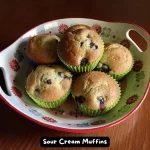 A plate of freshly baked sour cream muffins with blueberries, perfect for breakfast.